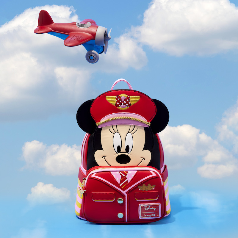 Mini backpack featuring Minnie Mouse as a pilot wearing a red and pink uniform, including pilot's cap. The bag sits against a background that looks like the sky with a red and blue plane flying above it. 